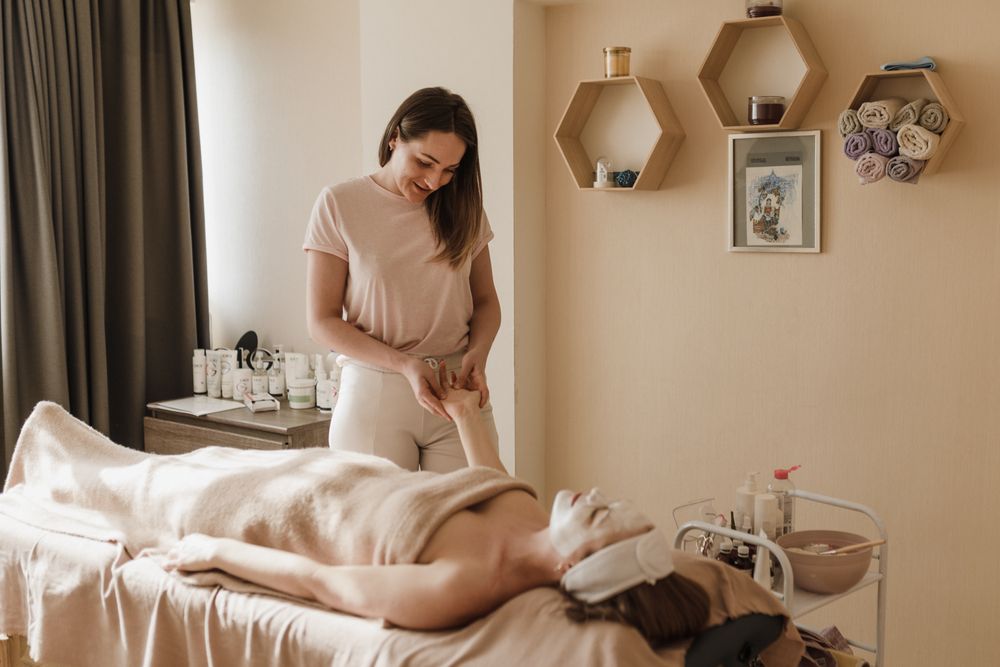 Heller, warm eingerichteter Behandlungsraum mit Liege, Handtüchern und Naturprodukten